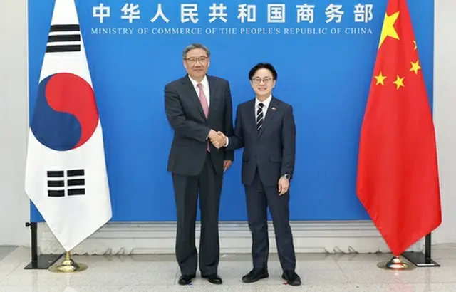 握手する金正官産業通商資源部長官（右）と王文濤商務相（同部提供）＝（聯合ニュース）≪転載・転用禁止≫