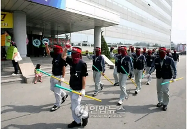 覆面で顔を隠し、鉄パイプを手に救済を訴えながら本社前を練り歩く双竜自労組＝5日、平沢（聯合ニュース）