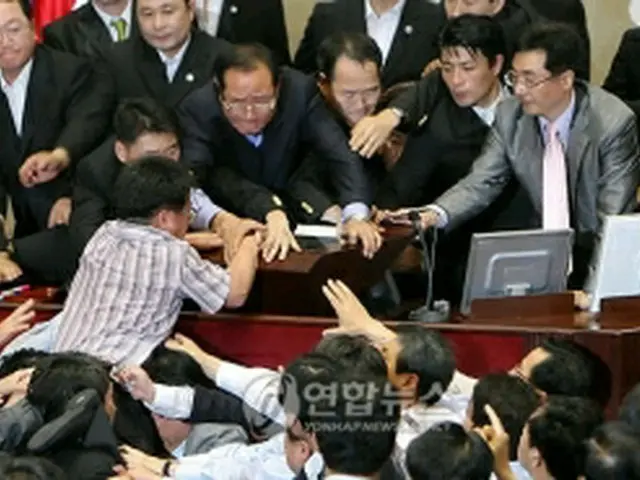 法の通過を阻止しようと議長席に詰め掛ける民主党議員＝22日、ソウル（聯合ニュース）