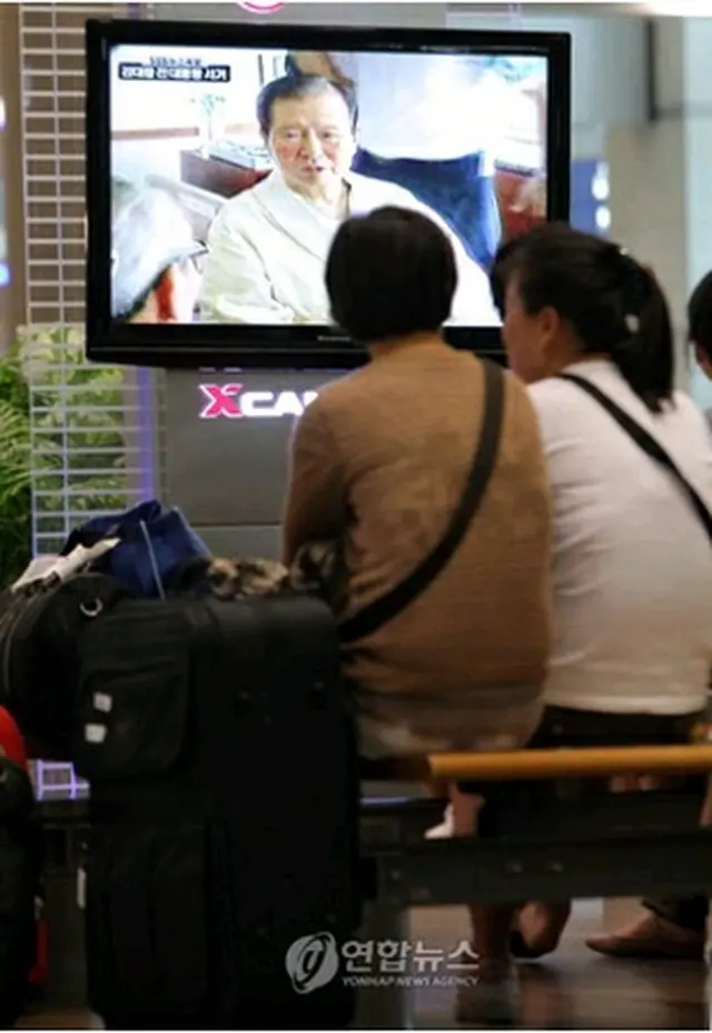 仁川国際空港で逝去のニュースに見入る旅行客ら＝18日、永宗島（聯合ニュース）