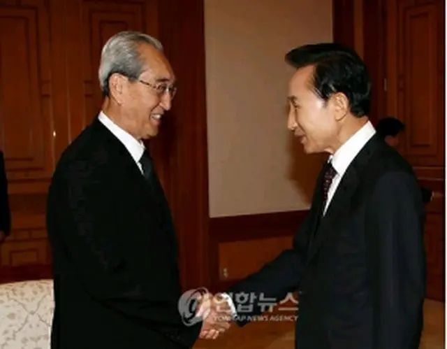 金秘書（左）と握手を交わす李大統領（青瓦台提供）＝23日、ソウル（聯合ニュース）