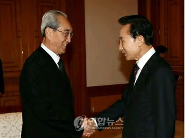 金秘書（左）と握手を交わす李大統領（青瓦台提供）＝23日、ソウル（聯合ニュース）