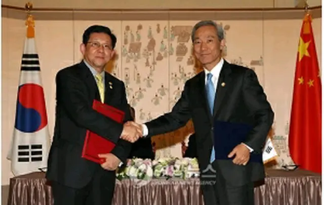 MOUに署名後、握手する金本部長（右）と陳商務部長＝28日、ソウル（聯合ニュース）