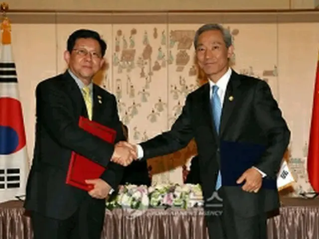 MOUに署名後、握手する金本部長(右)と陳商務部長=28日、ソウル(聯合ニュース)
