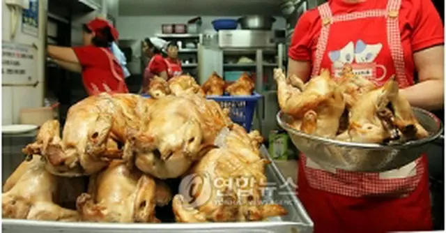 調理に追われるフライドチキン店の店員も韓国のチームカラー、赤いシャツ姿で＝（聯合ニュース）