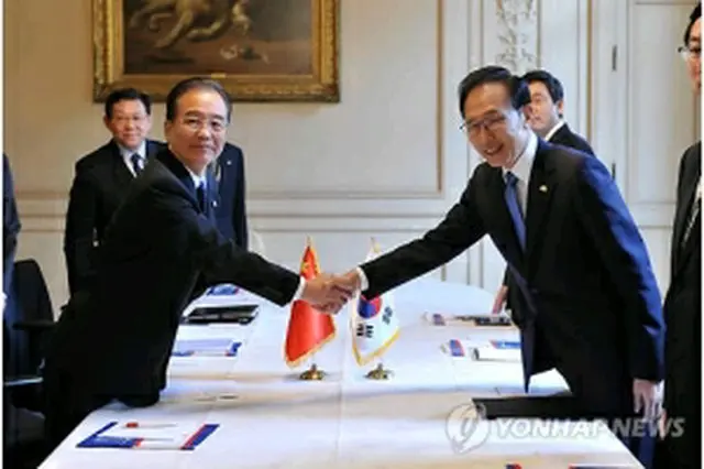会談に先立ち握手を交わす李大統領（右）と温首相＝5日、ブリュッセル（聯合ニュース）