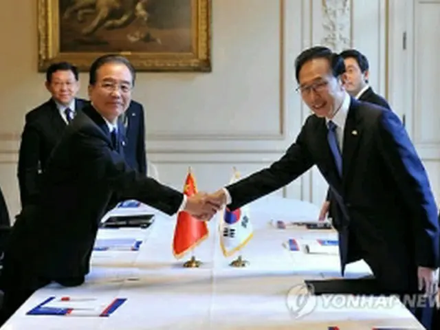 会談に先立ち握手を交わす李大統領（右）と温首相＝5日、ブリュッセル（聯合ニュース）