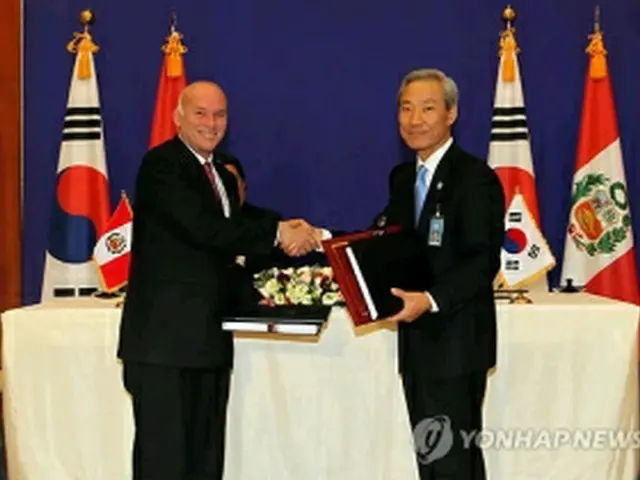 仮署名後、握手を交わす金本部長とペレス通商・観光相＝15日、ソウル（聯合ニュース）