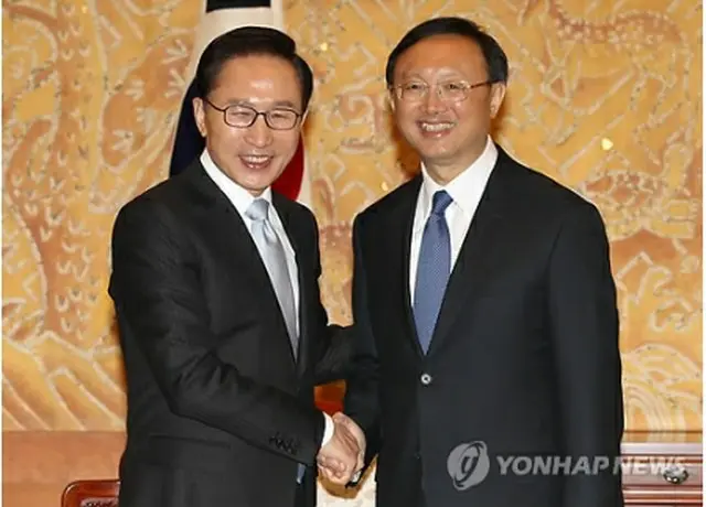 固く握手する李大統領（左）と楊外相＝23日、ソウル（聯合ニュース）