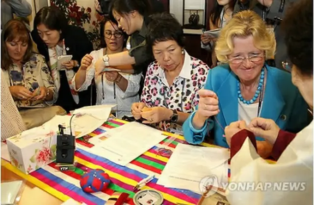 刺繍体験に挑戦する夫人ら＝19日、ソウル（聯合ニュース）
