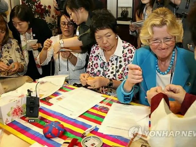 刺繍体験に挑戦する夫人ら＝19日、ソウル（聯合ニュース）