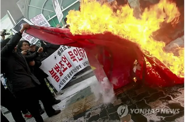 中国国旗を燃やして抗議する韓国の保守団体関係者ら＝13日、ソウル（聯合ニュース）