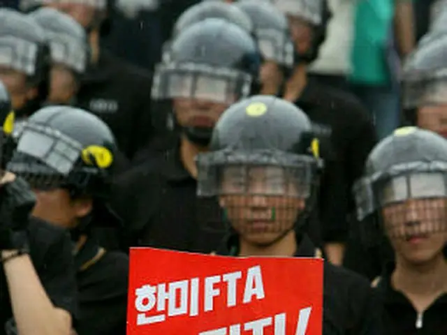 記者会見を進めようとする反韓米ＦＴＡ団体の会員と、警備に立つ警察＝１０日、ソウル（聯合）