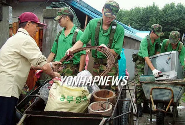 京畿道南楊州市で家財道具を運ぶ住民と復旧援を助ける陸軍部隊＝１８日、楊州市（聯合）