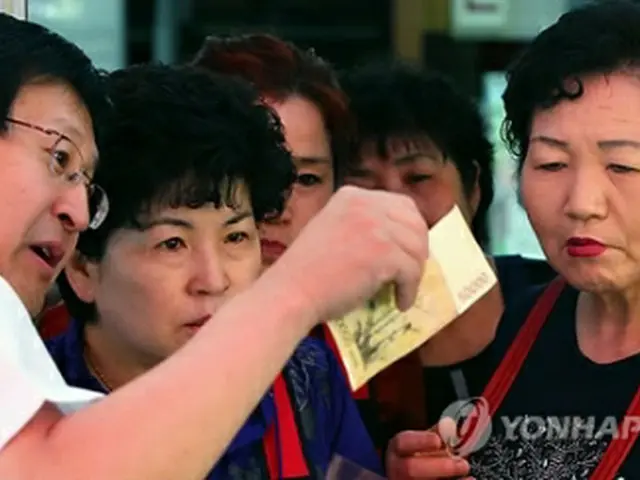 商店街で偽造紙幣の識別法を説明する韓国銀行関係者＝（聯合ニュース）