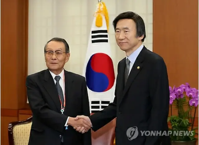 握手を交わす尹長官（右）と佐々木会長＝23日、ソウル（聯合ニュース）