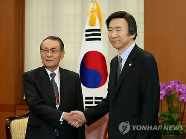 握手を交わす尹長官（右）と佐々木会長＝23日、ソウル（聯合ニュース）