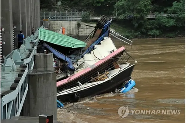 江原道・春川にある衣巖ダムの水門に流れてきたボートがかかっている＝15日、春川（聯合ニュース）