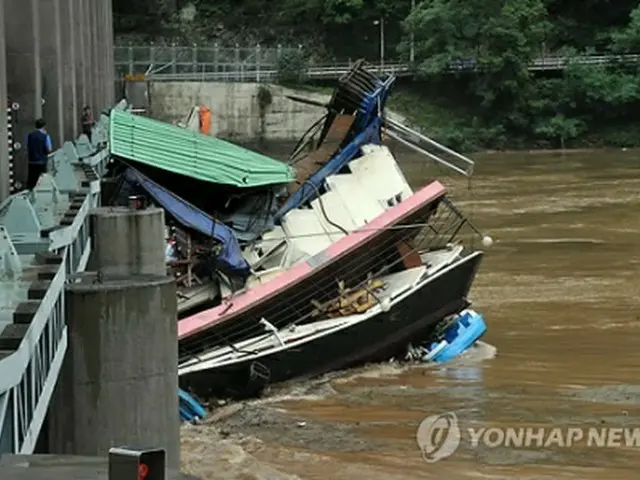 江原道・春川にある衣巖ダムの水門に流れてきたボートがかかっている＝15日、春川（聯合ニュース）