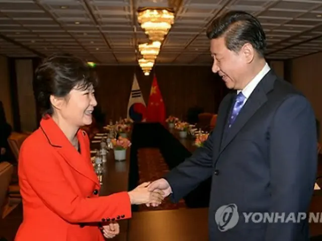 首脳会談後、握手する朴大統領（左）と習主席＝23日、ハーグ（聯合ニュース）