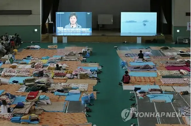 事故現場近くの体育館で朴大統領の談話発表を聞く犠牲者の家族ら＝１９日、珍島（聯合ニュース）