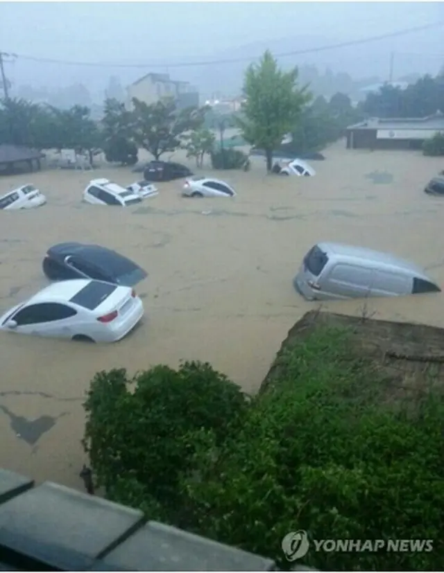 浸水した道路で水に流される車両＝25日、釜山（聯合ニュース）
