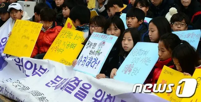 在大韓民国日本国大使館の前で、韓国の子供たちが日本政府の謝罪を促す垂れ幕や札を掲げ、元慰安婦問題解決のための定期水曜デモに参加した。
