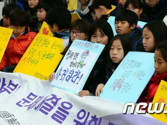 在大韓民国日本国大使館の前で、韓国の子供たちが日本政府の謝罪を促す垂れ幕や札を掲げ、元慰安婦問題解決のための定期水曜デモに参加した。