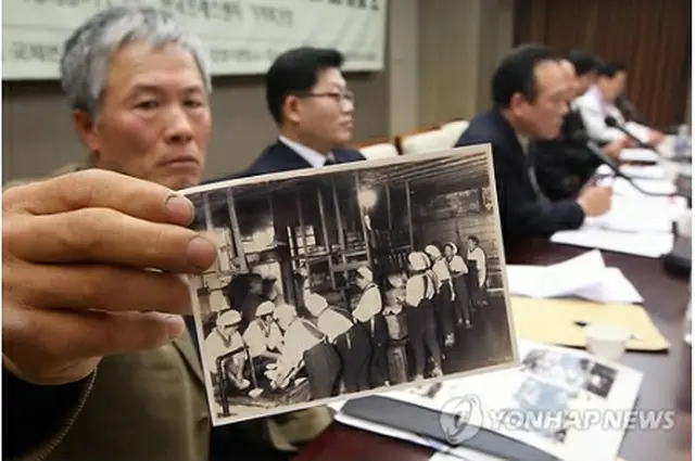 強制徴用の実情を示す写真を公開する遺族会関係者＝２４日、ソウル（聯合ニュース）