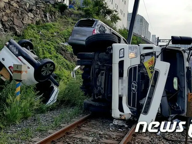 韓国・釜山市内で下水処理作業をしていた浄化槽タンクローリーの車両が、ブレーキの破裂によって下り坂を下っていき、周辺に駐車されていた車と共に線路上に転落する事故が発生した。（提供:news1）