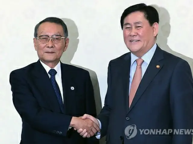 握手を交わす崔副首相（右）と佐々木会長＝１２日、ソウル（聯合ニュース）