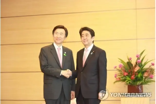 握手を交わす尹長官（左）と安倍首相＝２２日、東京（聯合ニュース）