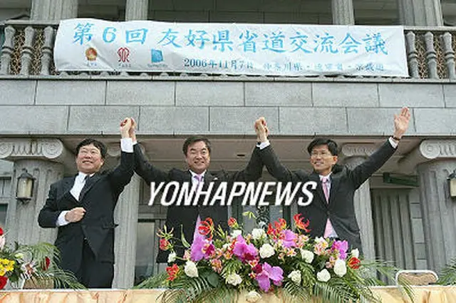 覚書締結式で手を取り合う金文洙・京畿道知事（右端）、松沢成文・神奈川県知事（中央）、許衛国・遼寧省副省長＝7日（聯合）