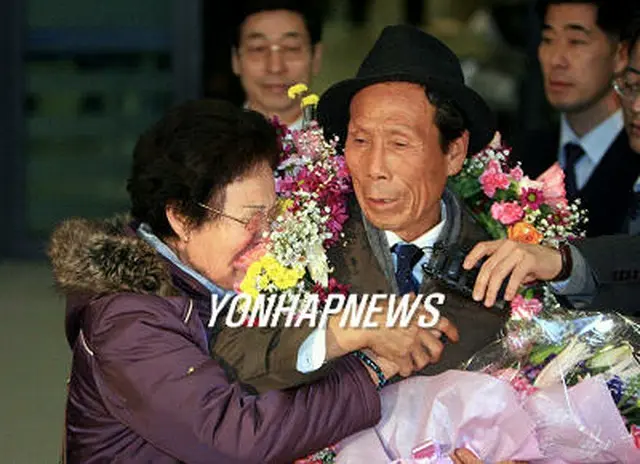 空港で出迎えた夫人と手を握り合うチェ・ウクイルさん＝16日、永宗島（聯合）