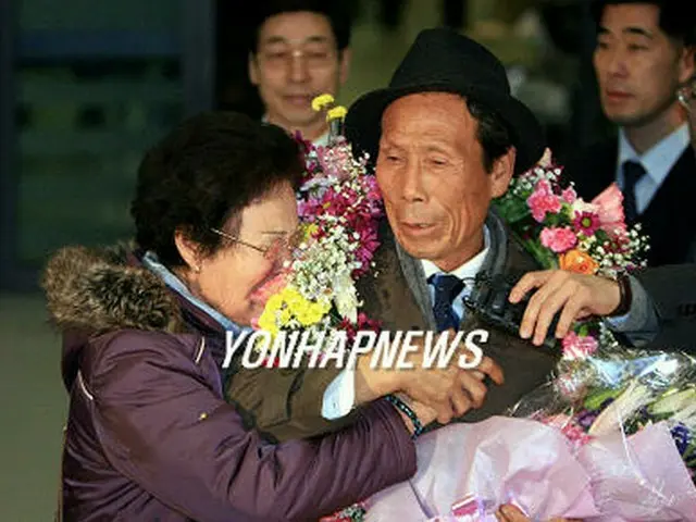 空港で出迎えた夫人と手を握り合うチェ・ウクイルさん＝16日、永宗島（聯合）