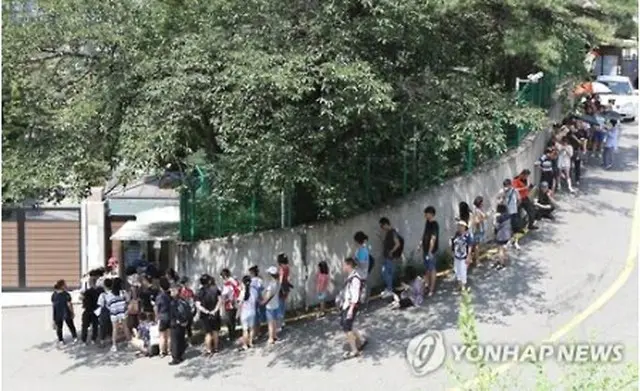 ビザの発給を受けるため、在韓中国大使館前で並ぶ人たち＝４日、ソウル（聯合ニュース）