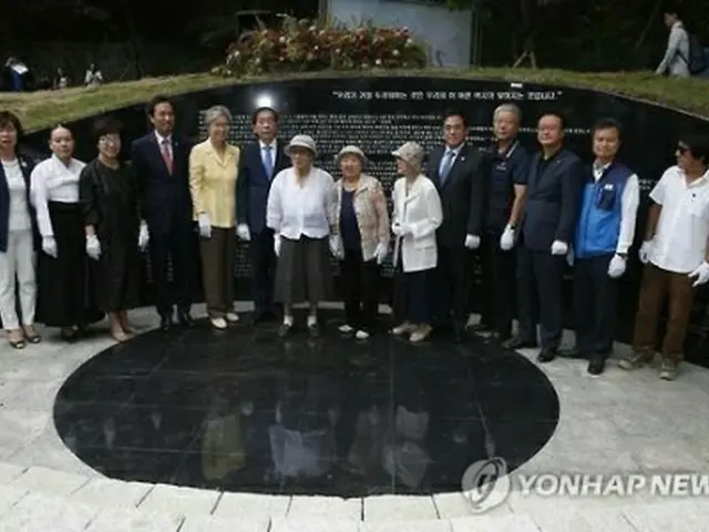 慰安婦被害者２４７人の名前や証言などが記された造形物の前で記念撮影する出席者ら＝２９日、ソウル（聯合ニュース）