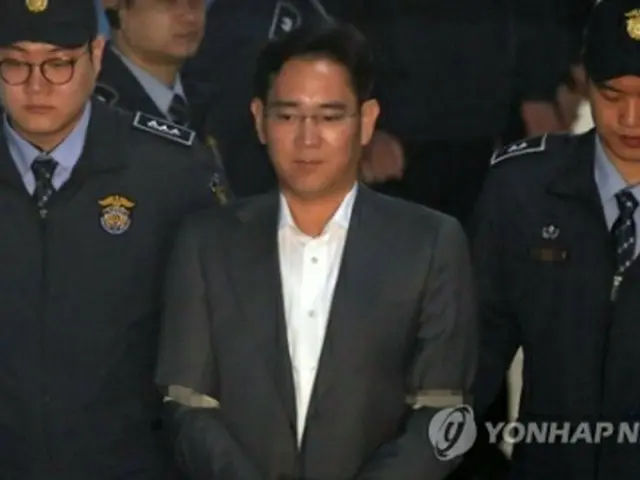 護送車で地裁に到着し、法廷に向かう李被告＝７日、ソウル（聯合ニュース）