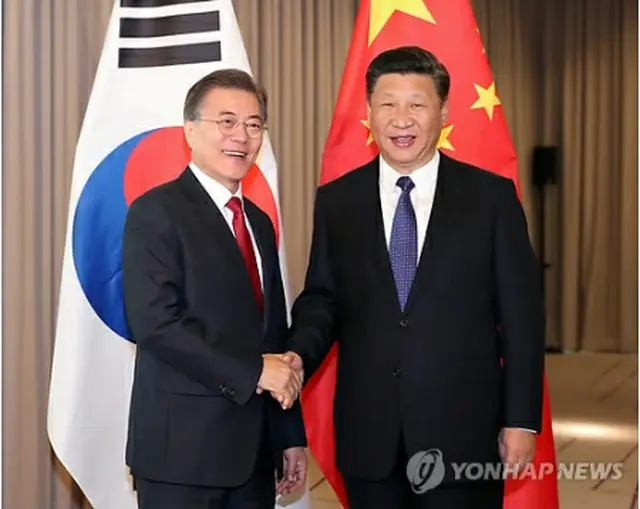 首脳会談で握手を交わす文大統領（左）と習首席＝６日、ベルリン（聯合ニュース）