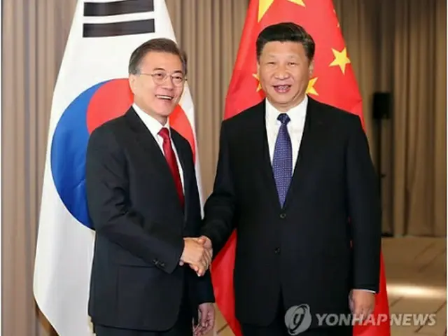 首脳会談で握手を交わす文大統領（左）と習首席＝６日、ベルリン（聯合ニュース）