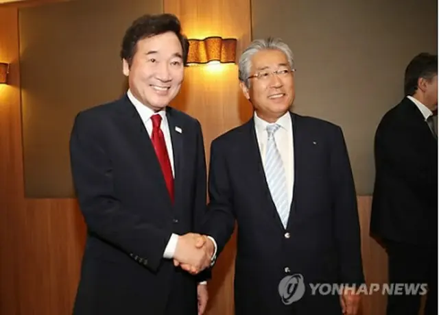 日本オリンピック委員会（ＪＯＣ）の竹田恒和会長（右）と握手を交わす李首相＝２４日、オリンピア（聯合ニュース）