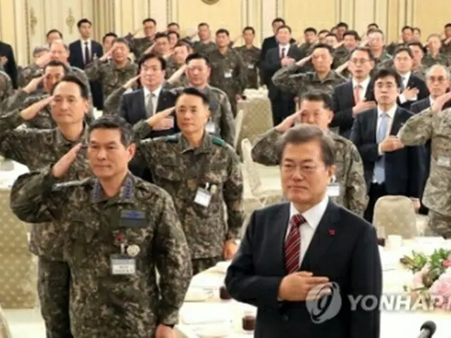 昼食会で国旗に敬礼する文大統領（手前右）と軍の指揮官ら＝８日、ソウル（聯合ニュース）