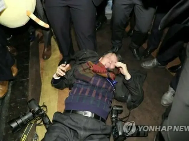 暴行を受けて倒れている韓国人記者＝１４日、北京（聯合ニュース）