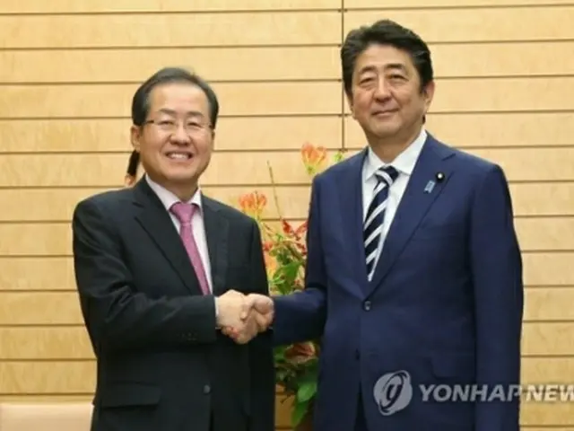 安倍首相と握手する洪代表（左、自由韓国党提供）＝１４日、東京（聯合ニュース）