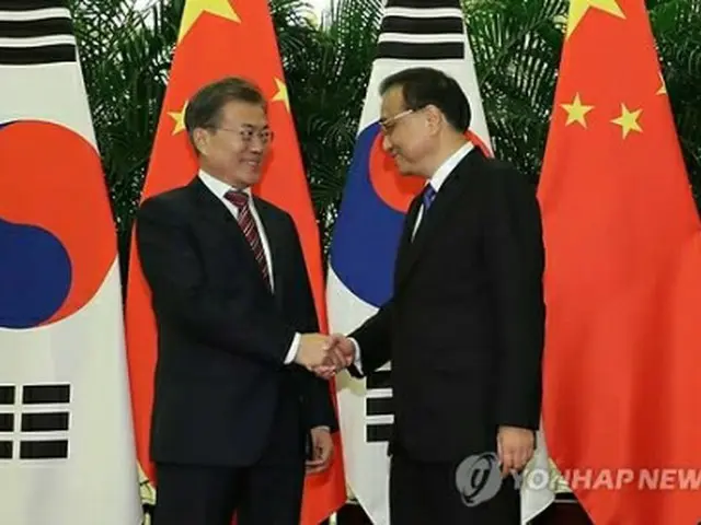 李克強首相（右）と握手する文大統領＝１５日、北京（聯合ニュース）