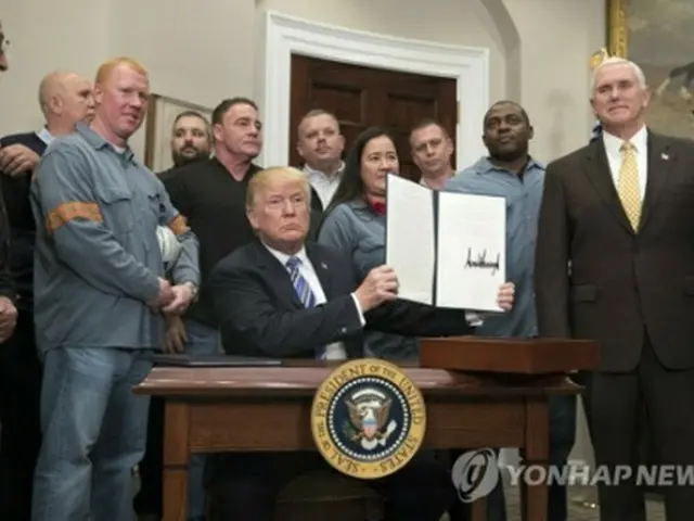 自らが署名した輸入制限の文書を掲げるトランプ氏＝８日、ワシントン（ＥＰＡ＝聯合ニュース）
