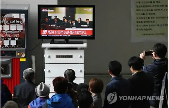 判決公判が開かれたソウル中央地裁に設置されているテレビで生中継を見る市民たち＝６日、ソウル（聯合ニュース）