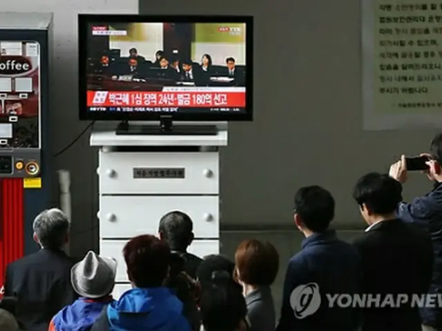 判決公判が開かれたソウル中央地裁に設置されているテレビで生中継を見る市民たち＝６日、ソウル（聯合ニュース）