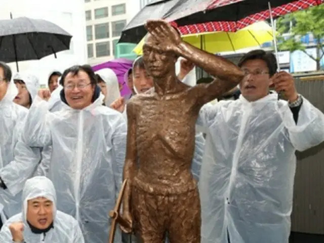 釜山の日本総領事館前で、徴用工像の模型を置き集会を開く市民団体の会員たち＝２４日、釜山（聯合ニュース）