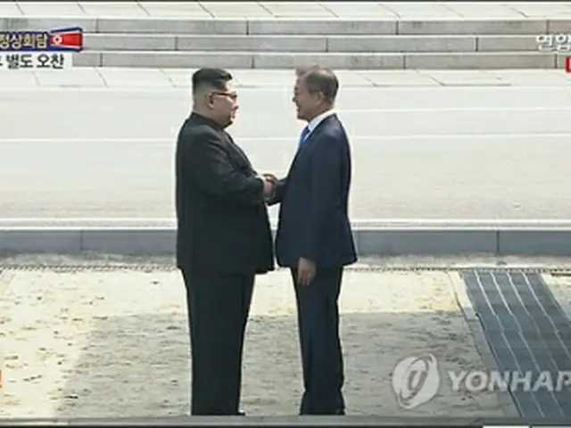 軍事境界線の北朝鮮側で握手を交わす文大統領（右）と金委員長＝２７日、板門店（聯合ニュースＴＶ）